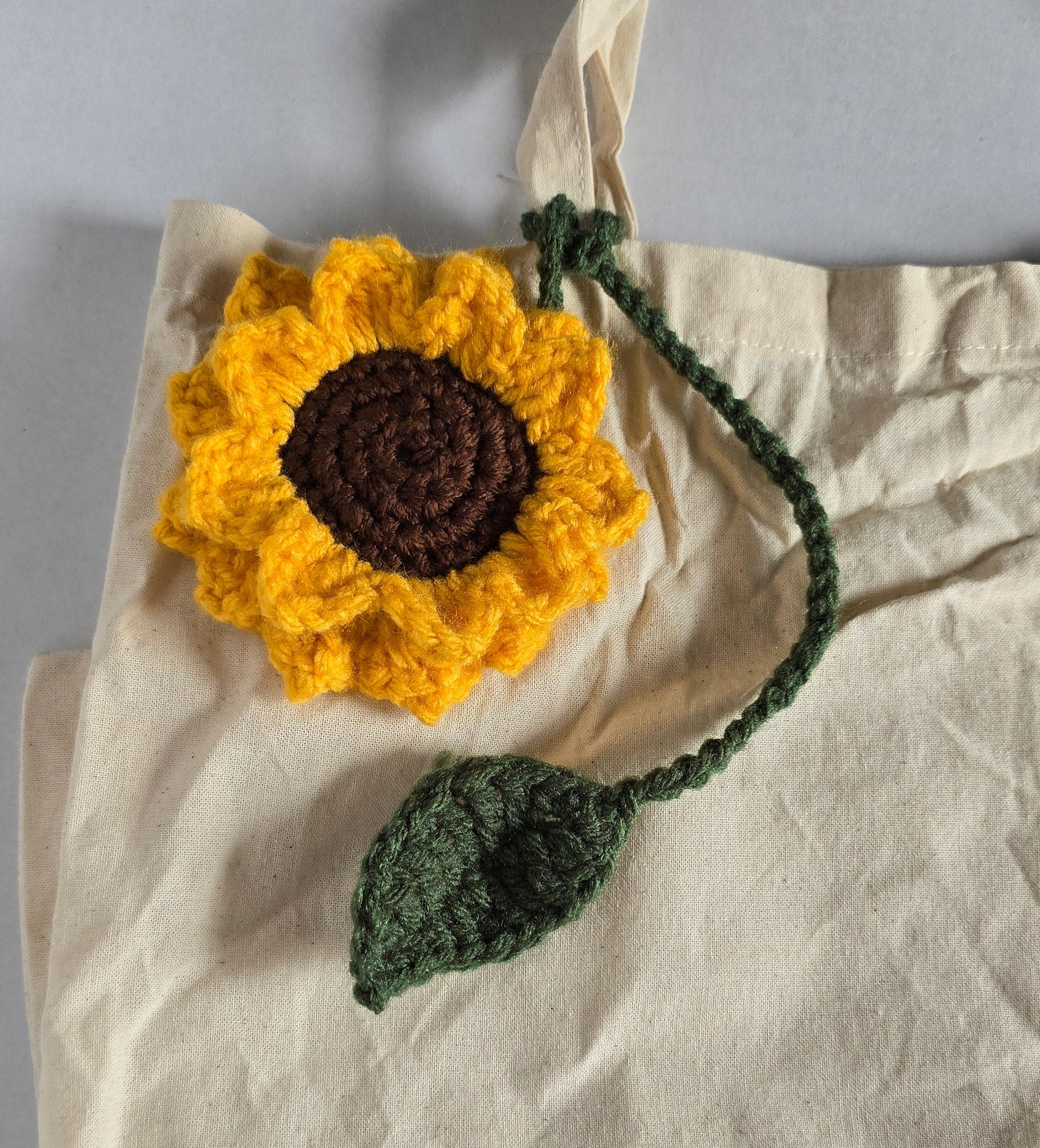 Crocheted sunflower with a brown center displayed on a canvas tote bag